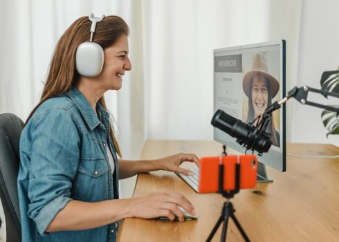 Cheerful woman browsing computer and recording podcast photo