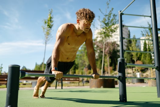 Strong young sportsman doing calisthenics at the park photo