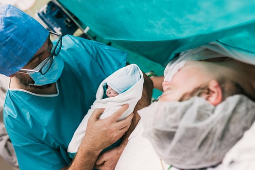 Male doctor showing newborn baby to mother photo