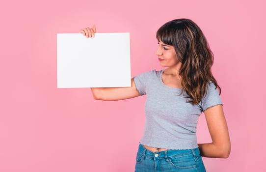 Woman holding a blank sign against a pink background photo