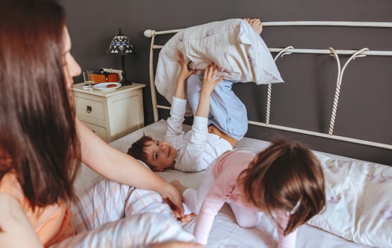 Relaxed mother and sons playing over the bed photo
