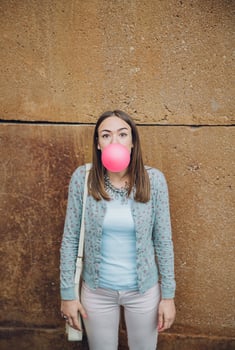 Young teenage girl blowing pink bubble gum photo