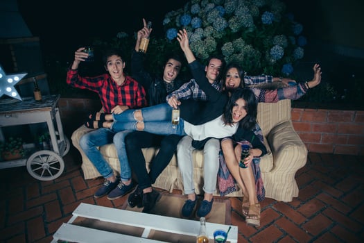 Woman lying over her friends sitting on sofa in a party photo