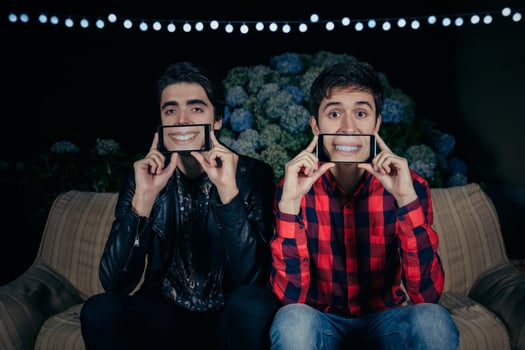 Funny young men holding smartphones showing female mouths smiling photo