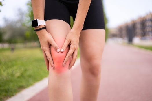 A woman with knee pain on a road. photo