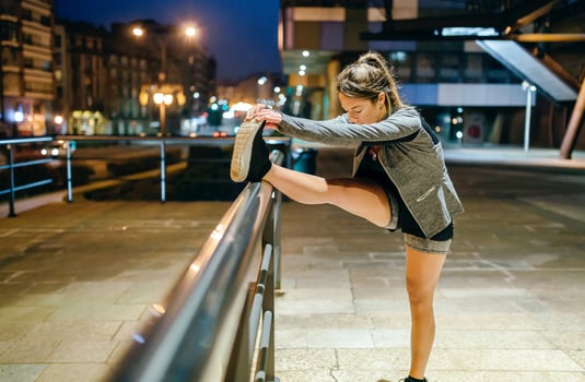 Woman runner stretching her leg before training at night on town photo