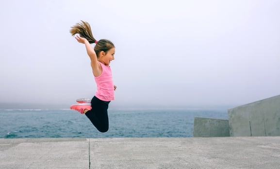 Little girl jumping by sea pier photo