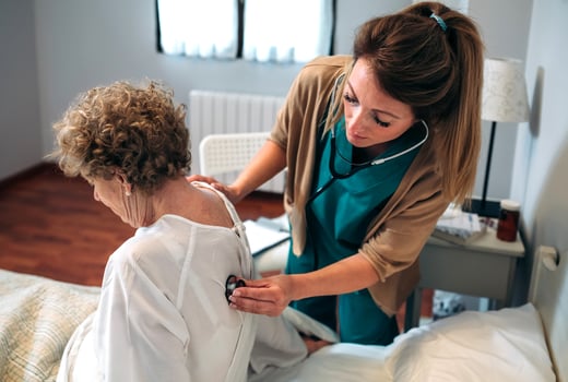 A nurse checking the heart rate of an elderly woman photo