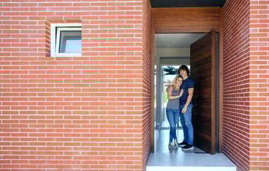 A man and woman standing in front of a brick house photo