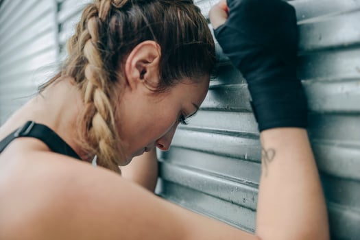 Tired sportswoman resting on a metal wall photo