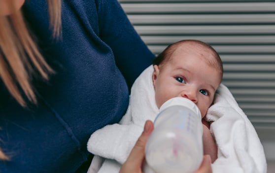 A woman is feeding a baby with a bottle photo