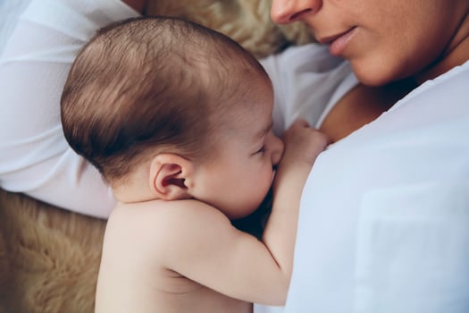Newborn lying on the bed embraced by her mother photo