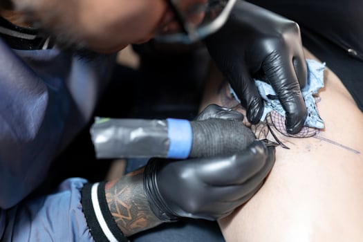 A tattoo artist is tattooing a snake and a rose on a woman's leg. Close up. photo
