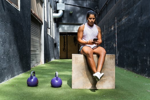 Ethnic woman browsing smartphone on jump box photo