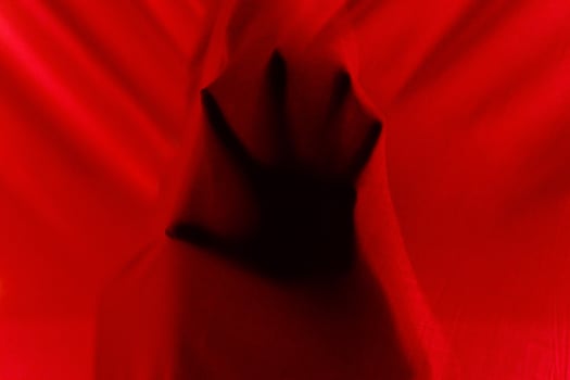 Faceless person hiding behind curtains at night time photo