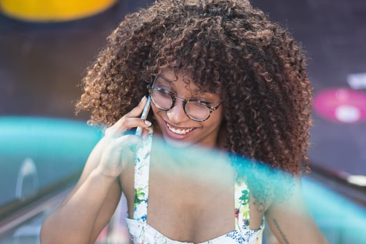 Glad African American woman speaking on smartphone in park photo