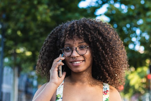A woman with glasses and a smile on her face is talking on her cell phone photo