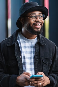 Positive black hipster man using mobile phone photo
