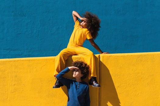 Black curly haired girl and boy resting near colorful wall photo