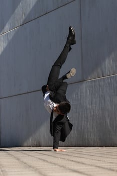 Ethnic businessman performing breakdance handstand on street photo