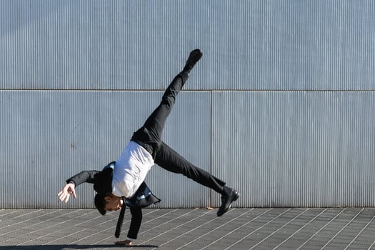 Ethnic businessman performing breakdance handstand on street photo