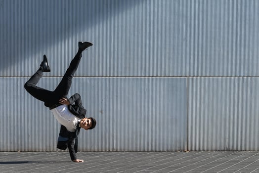 Ethnic businessman performing breakdance handstand on street. photo