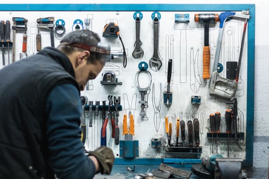 Professional mechanic using spanner while assembling vehicle engine details at workbench photo