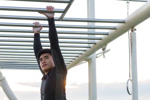 Ethnic sportsman exercising on monkey bars at the park photo