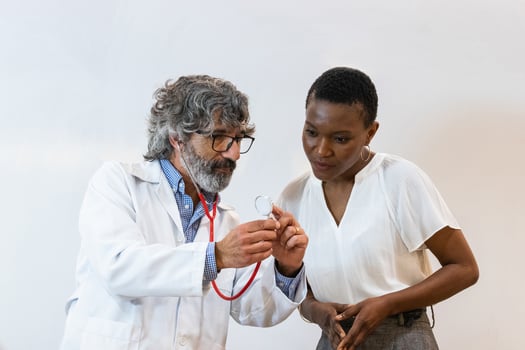 Elderly doctor showing stethoscope to patient photo
