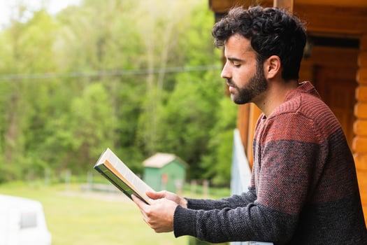 Thoughtful man reading book on terrace of house photo