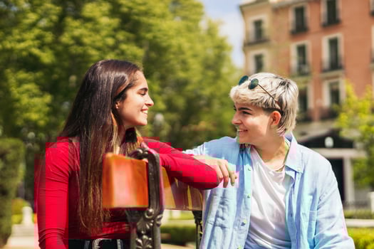 two teenager girls looking each other sitting on a bench photo