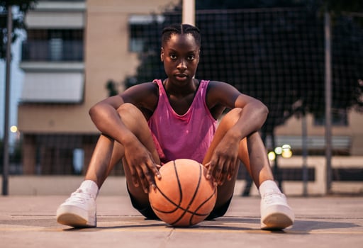 A young woman sitting on the ground with a basketball photo