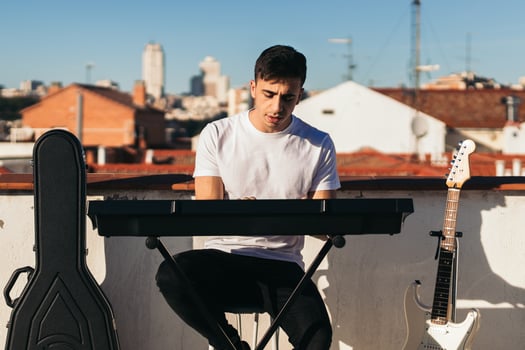 Front view of a man playing music keyboard on a rooftop. Young man performing photo