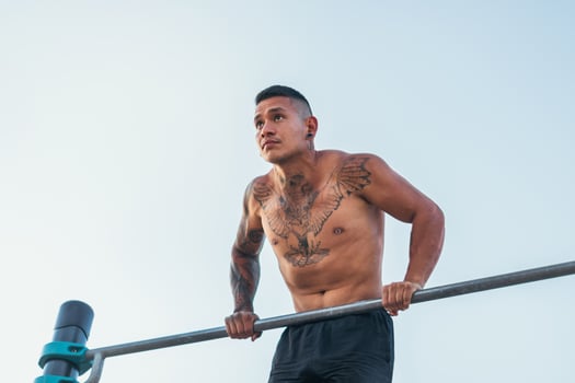 male athlete doing dips on a bar outdoors photo