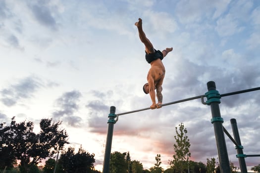 male athlete doing handstand on a bar in a calisthenic park photo