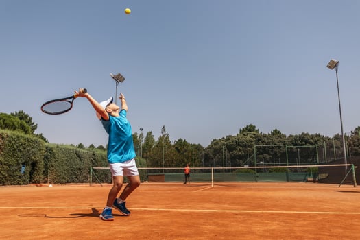 Boy playing tennis with his coach on a dirt court photo