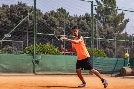 Man in sportswear playing tennis on a dirt tennis court photo