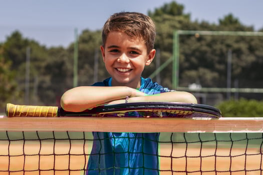 Little boy playing tennis on a dirt court photo