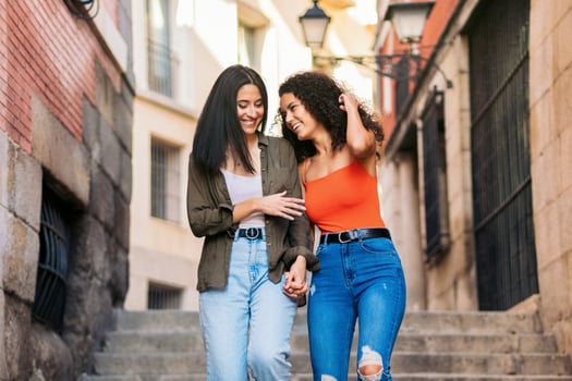 two young women going down street stairs smiling holding her hands photo