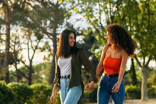 two young women couple walking holding her hands in a park photo