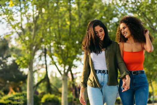 two young women couple walking holding her hands in a park. photo