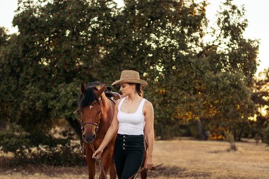 Young woman in hat walking with her horse photo