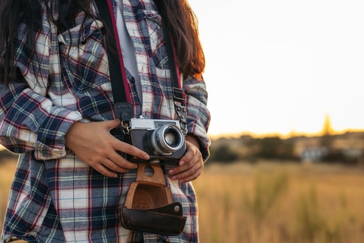 A woman holding a camera in a field photo