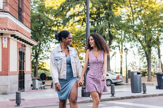 Two women walking across a street holding hands photo