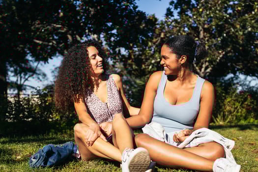 Two women sitting on the grass and talking photo