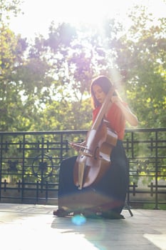 A young woman playing the cello on an outdoor stage photo