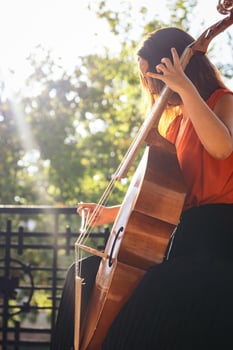 A young woman playing the cello on an outdoor stage photo