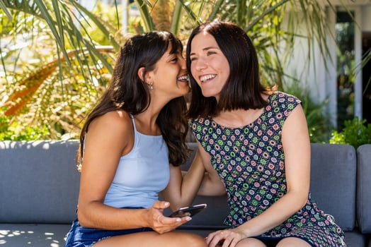 Beautiful woman whispering a secret to her best friend photo