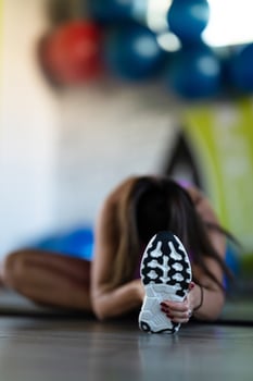 Woman Stretching in Gym. A athletic woman wearing a purple sports outfit is stretching her legs in a gym. photo