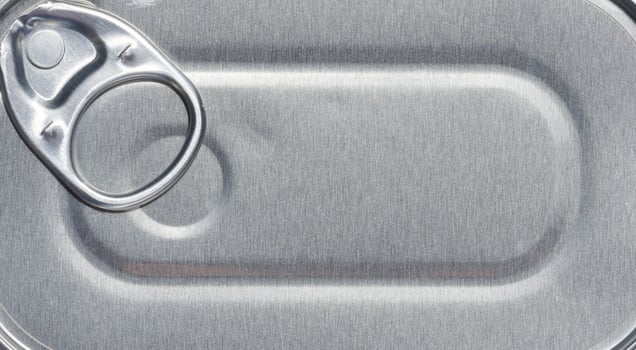Gray aluminum tin can lid with key, top view. Full frame photo